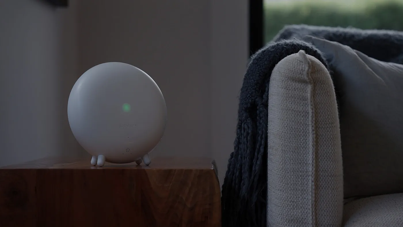 The Indoor Halo, a white speaker sphere, on a timber side table beside a sofa